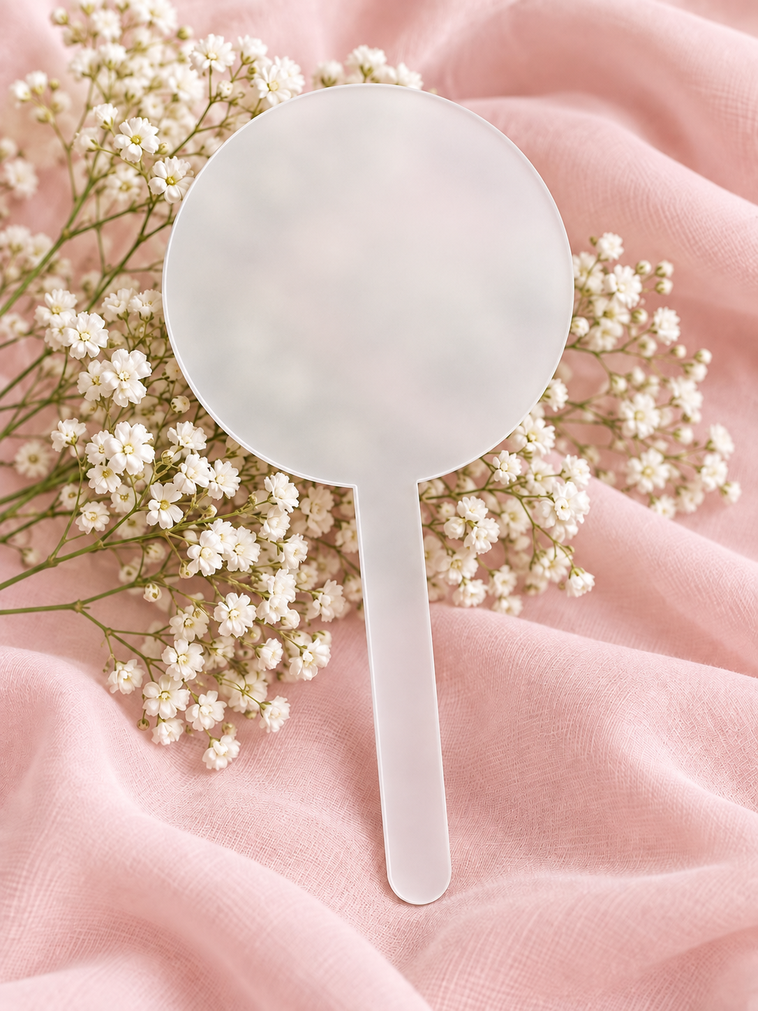 Frosted acrylic cake topper on soft pink fabric with baby's breath