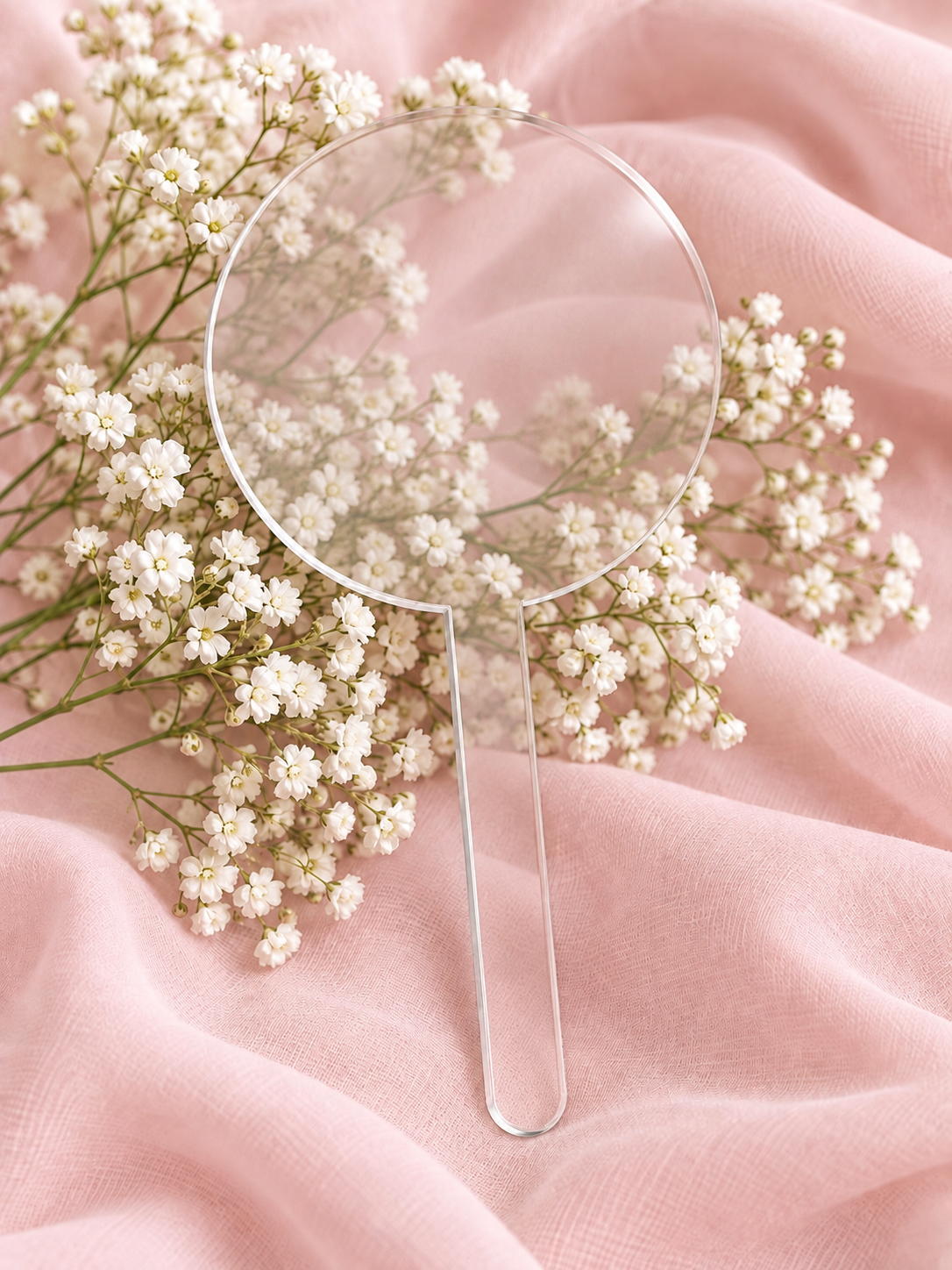Clear acrylic cake topper on soft pink fabric with baby's breath