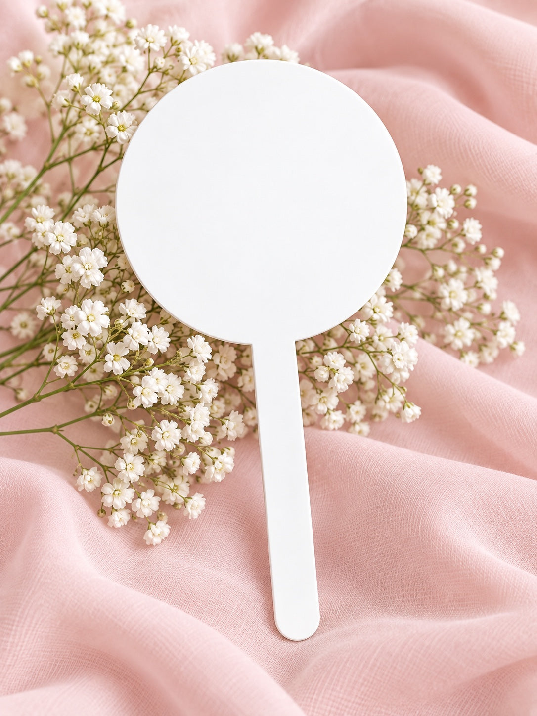 White acrylic cake topper on soft pink fabric with baby's breath